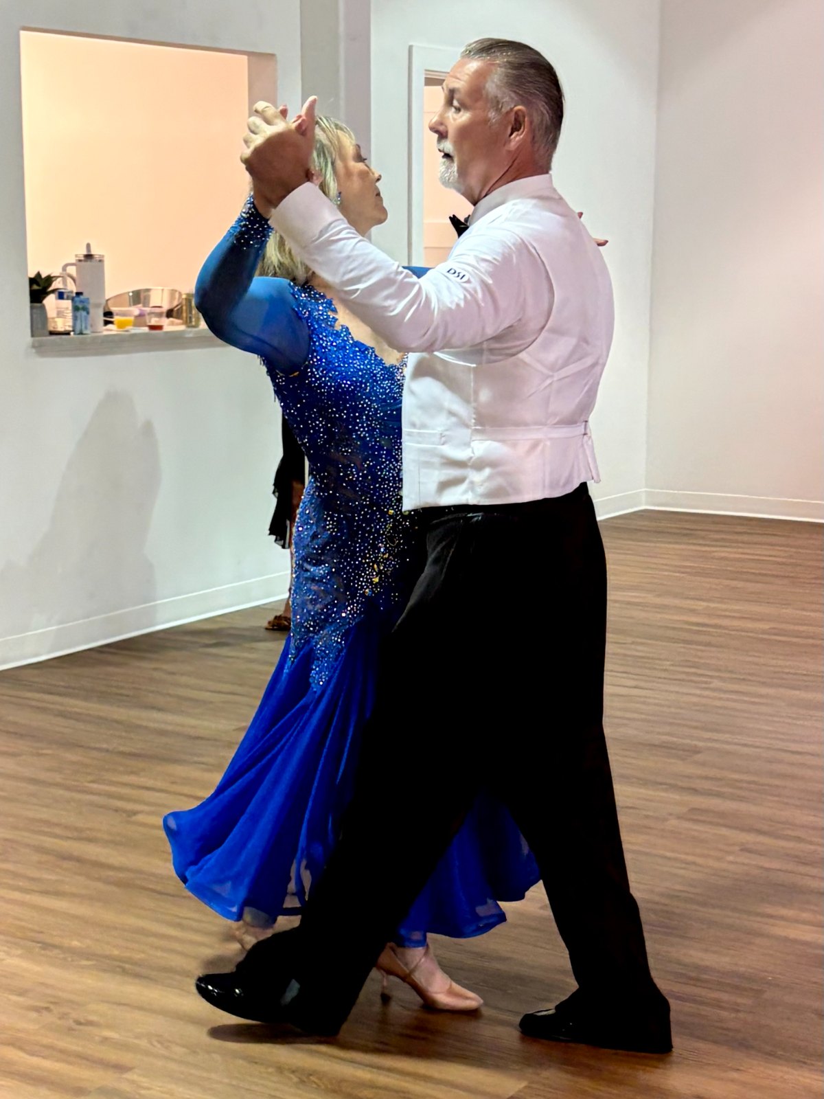 A couple in ballroom attire performing a smooth dance at the studio