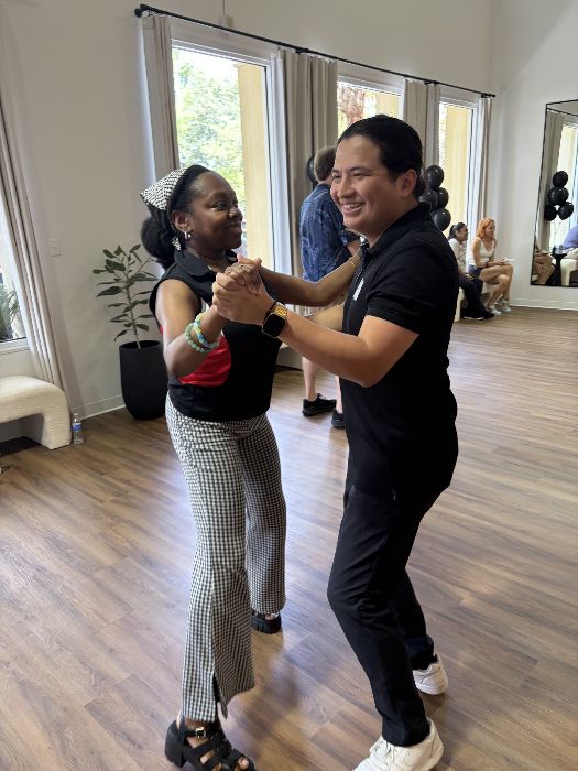A student and instructor mid-dance, laughing